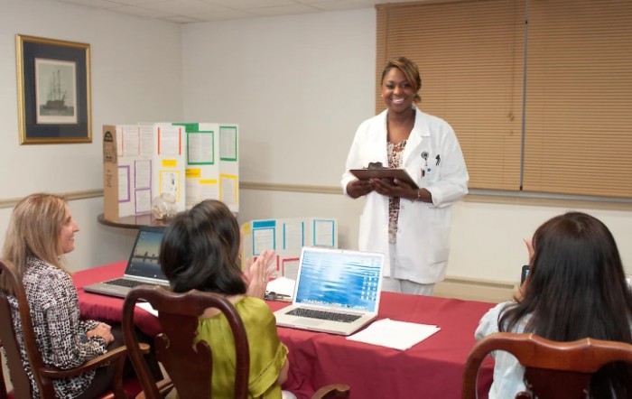 A doctor giving a presentation to an audience using laptops.