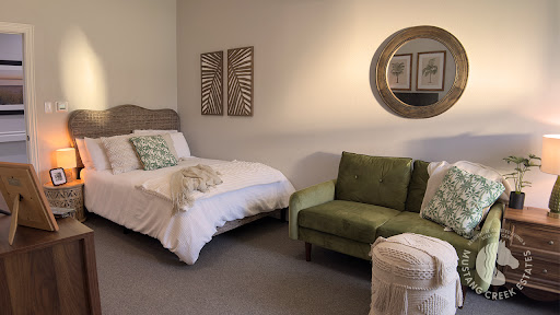A cozy and stylish bedroom featuring a single bed, green couch, and tasteful decor.
