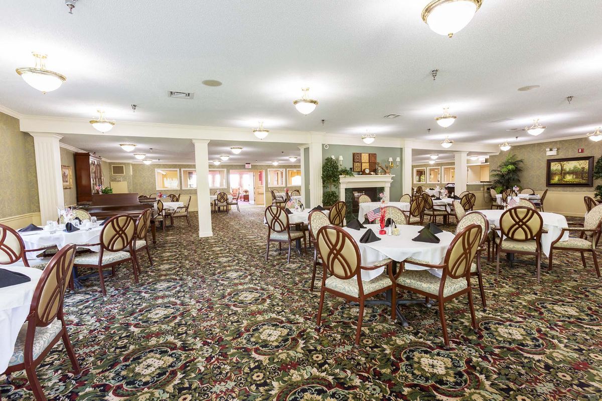 A spacious and elegantly decorated dining room with multiple tables and chairs set on a carpeted floor.