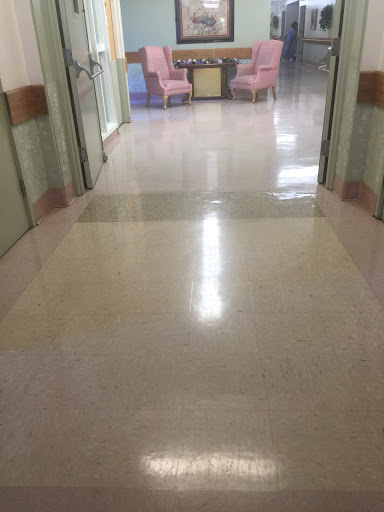 A clean hospital corridor with polished floors and soft lighting.