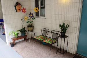 A cozy patio with a decorative bench, potted plants, and colorful wall decorations.