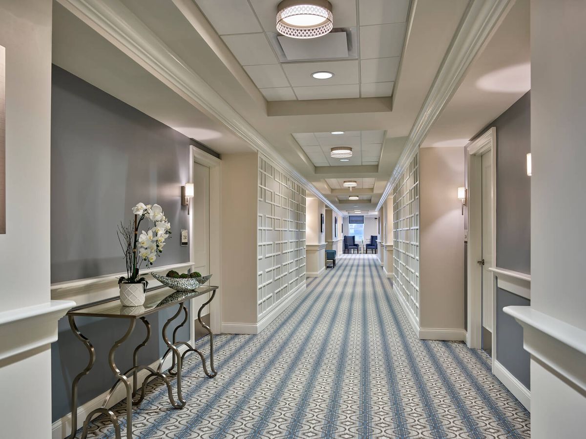 A modern hotel hallway with elegant decor and patterned carpeting.