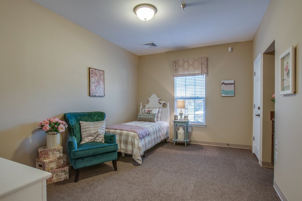 A cozy bedroom featuring a single bed and an armchair by the window.