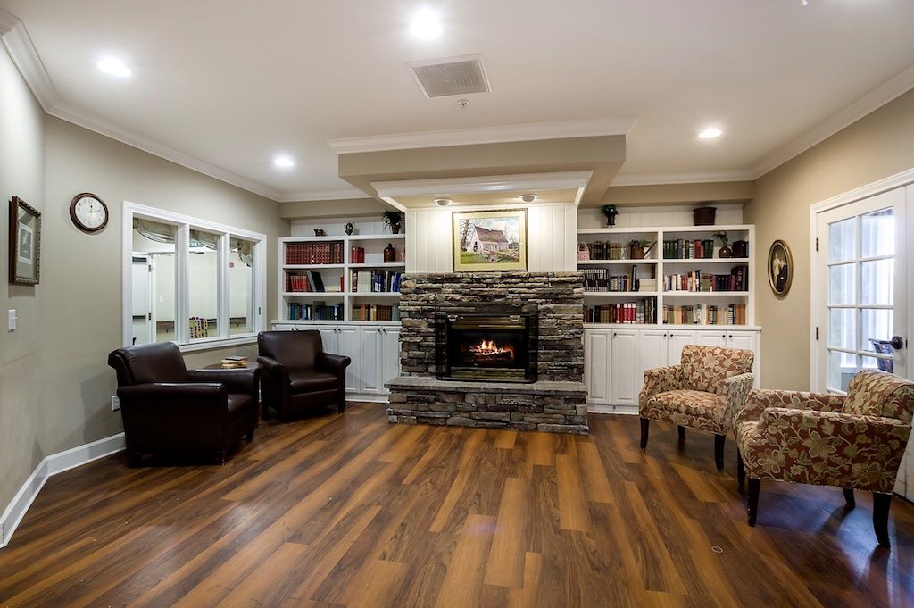 A cozy living room with a central fireplace surrounded by built-in bookshelves and comfortable armchairs on a wooden floor.