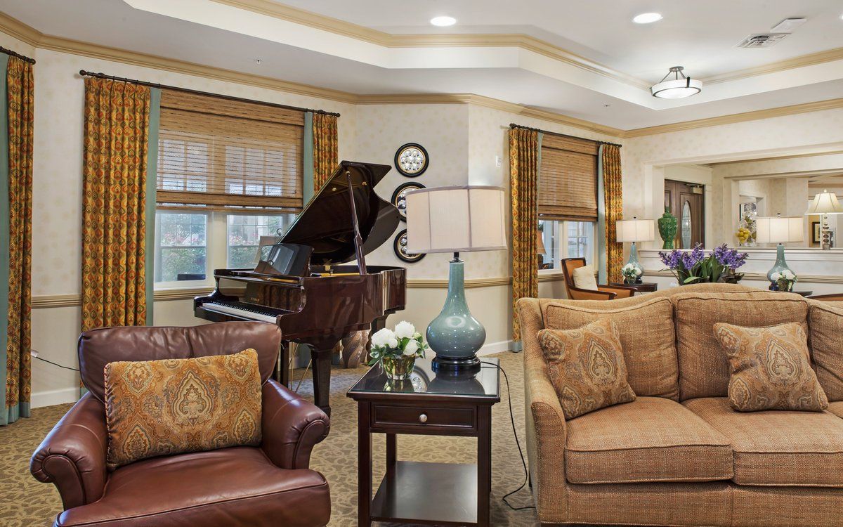 A well-decorated living room featuring a grand piano and comfortable seating arrangements.