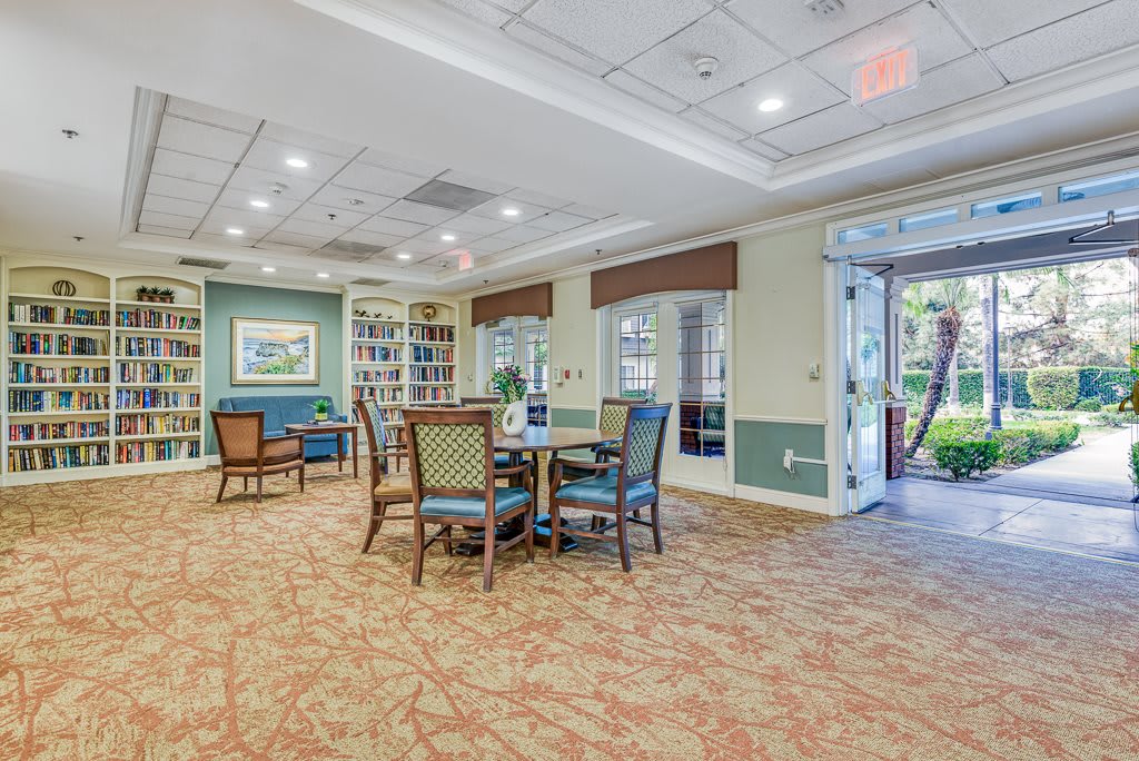 A well-lit room with comfortable seating and bookshelves, featuring a carpeted floor and windows.