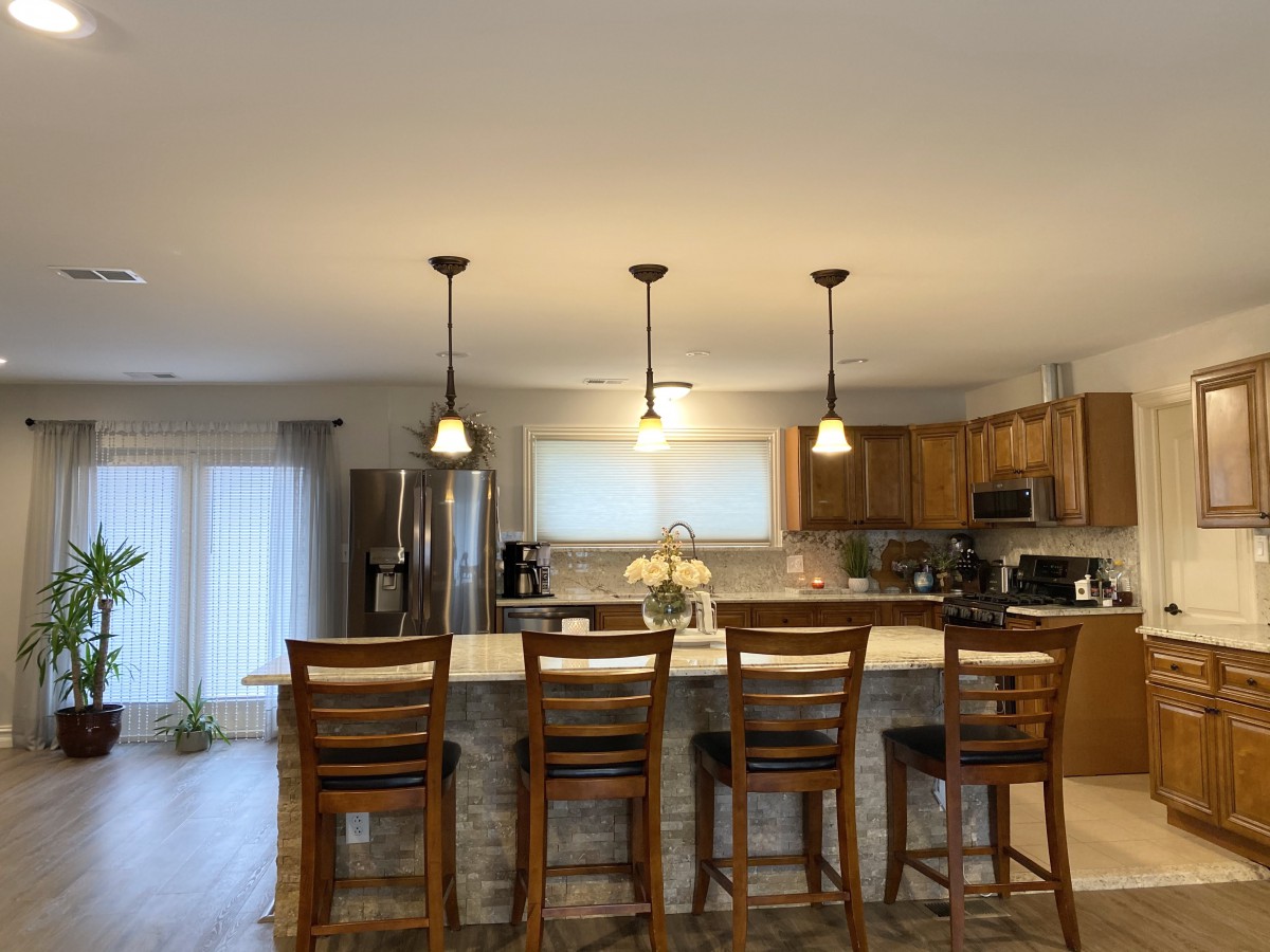 A modern kitchen with wooden cabinetry, an island with bar stools, and pendant lighting.