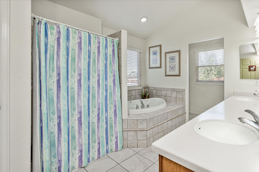 A serene and stylish bathroom featuring a shower with a colorful curtain and a spacious bathtub, accented by elegant tile work.