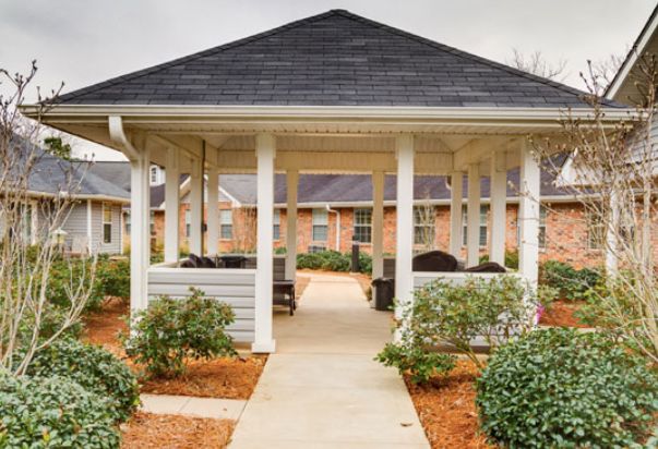 A charming gazebo surrounded by neatly landscaped gardens and a clear pathway.