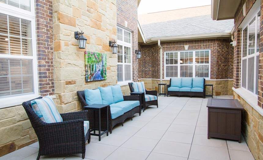 A cozy patio area with comfortable blue-cushioned seating and decorative lanterns.