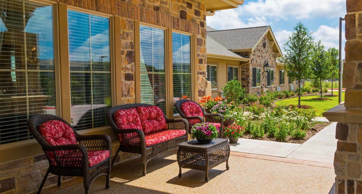 A cozy patio with wicker furniture and a beautifully landscaped garden in the background.