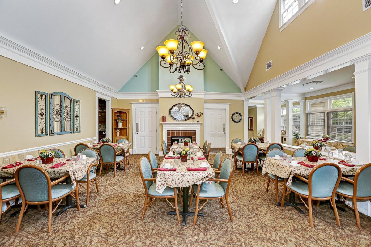 A spacious dining room with elegantly set tables and a grand chandelier.
