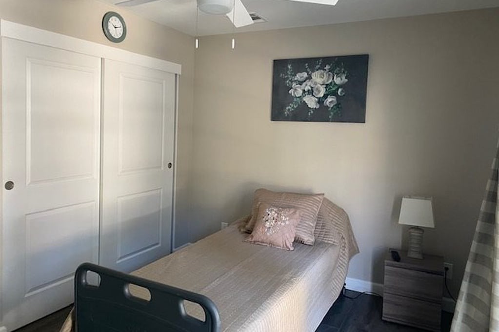 A minimalist bedroom with a single bed, nightstand, and decorative painting.