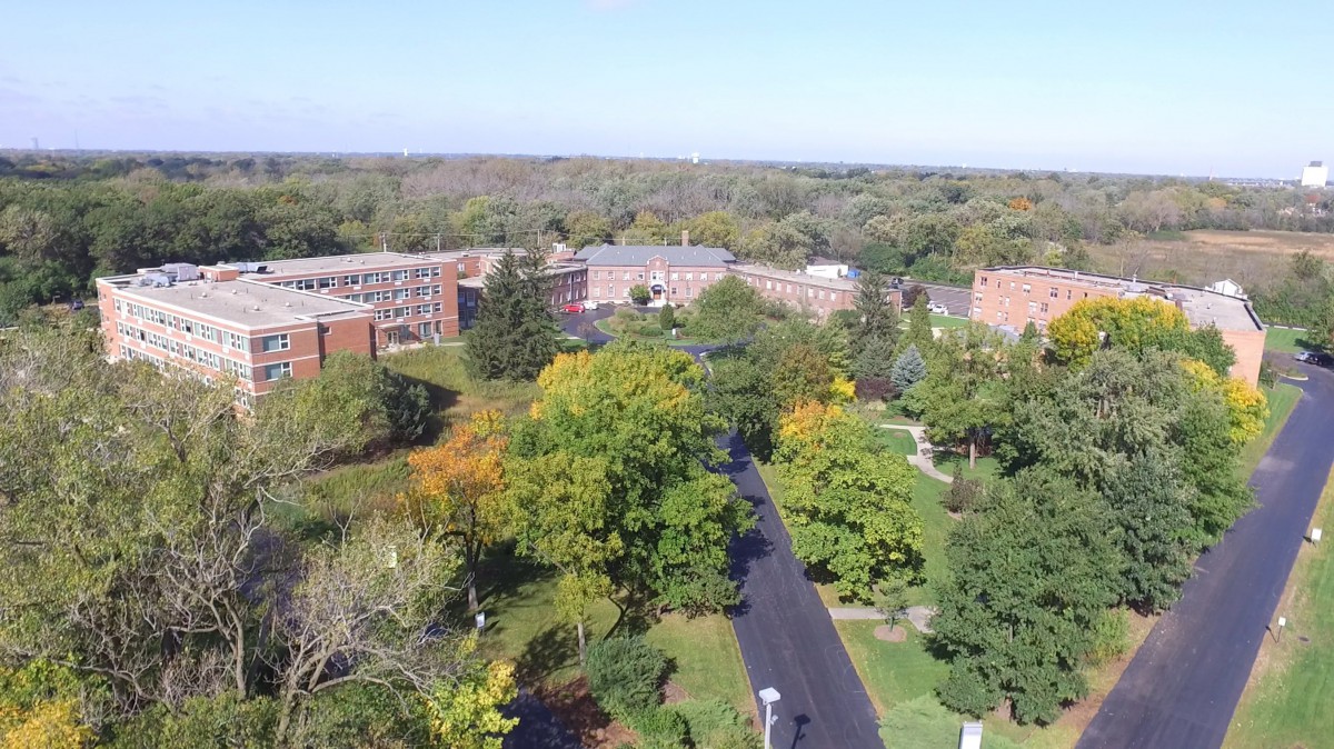 Aerial view of a campus surrounded by lush greenery and buildings.