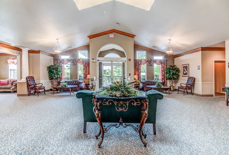 A spacious living room with elegant decor and furniture, featuring large windows and indoor plants.