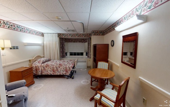 A cozy bedroom with a bed, table, and chairs near a window with curtains.