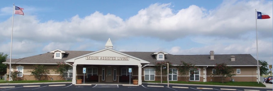 A public library building with a parking area in front, set against a backdrop of a partly cloudy sky.