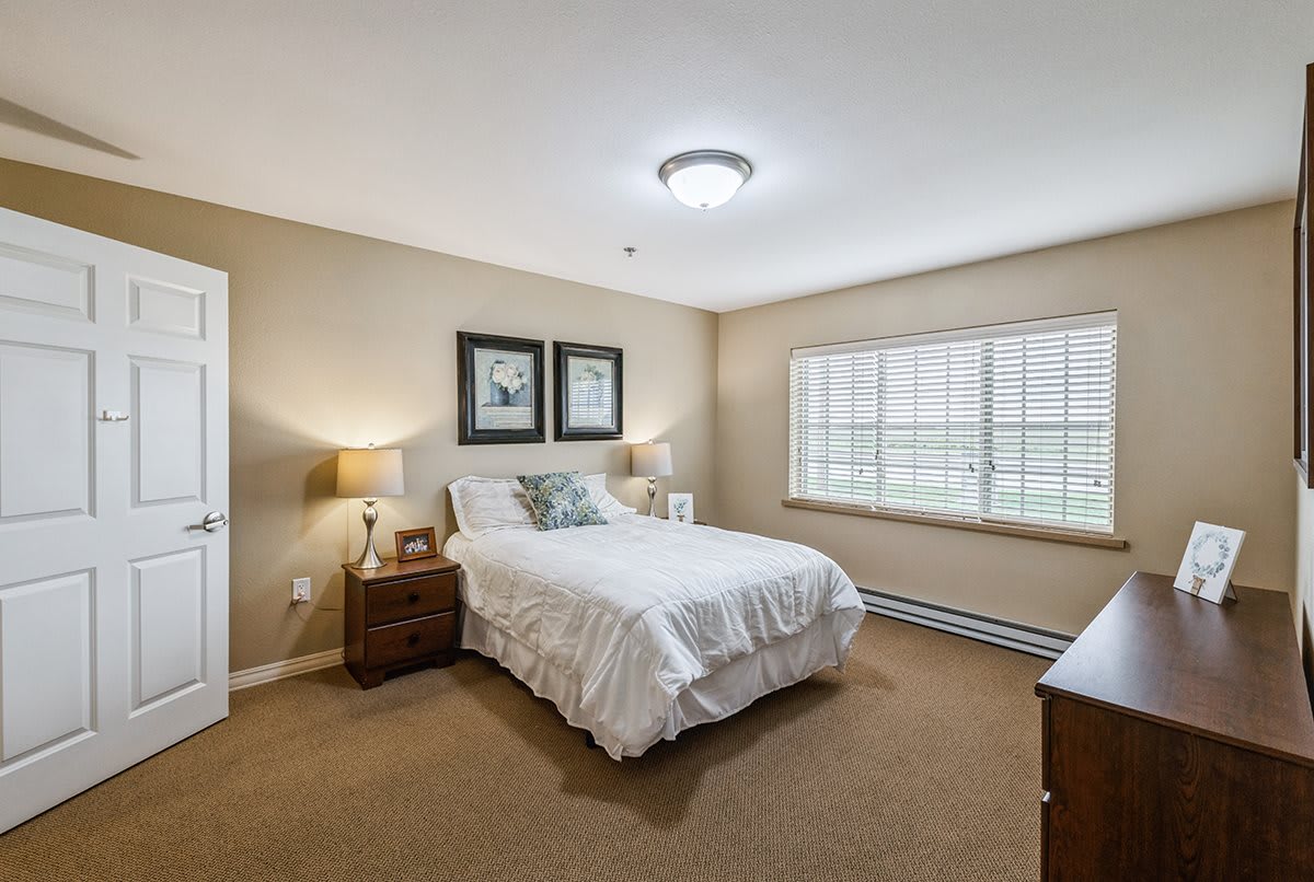 A cozy bedroom with a neatly made bed, bedside tables, and soft lighting.