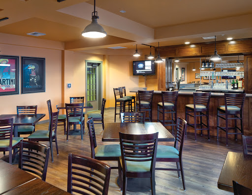 A well-lit dining area featuring tables and chairs, along with a bar setup in the background.