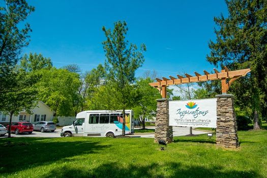 A shuttle bus parked near a sign at a park on a sunny day.