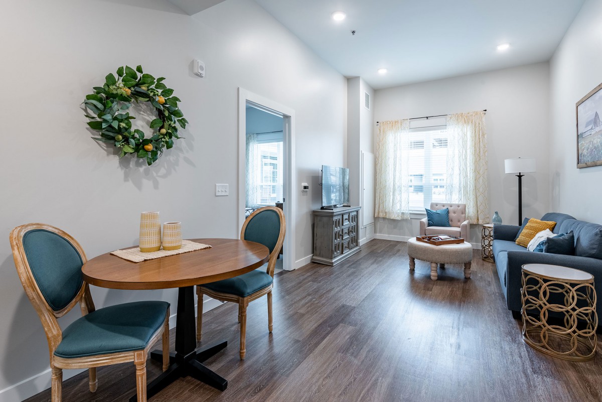 A modern living and dining area with wood flooring, featuring stylish furniture and ample natural light.