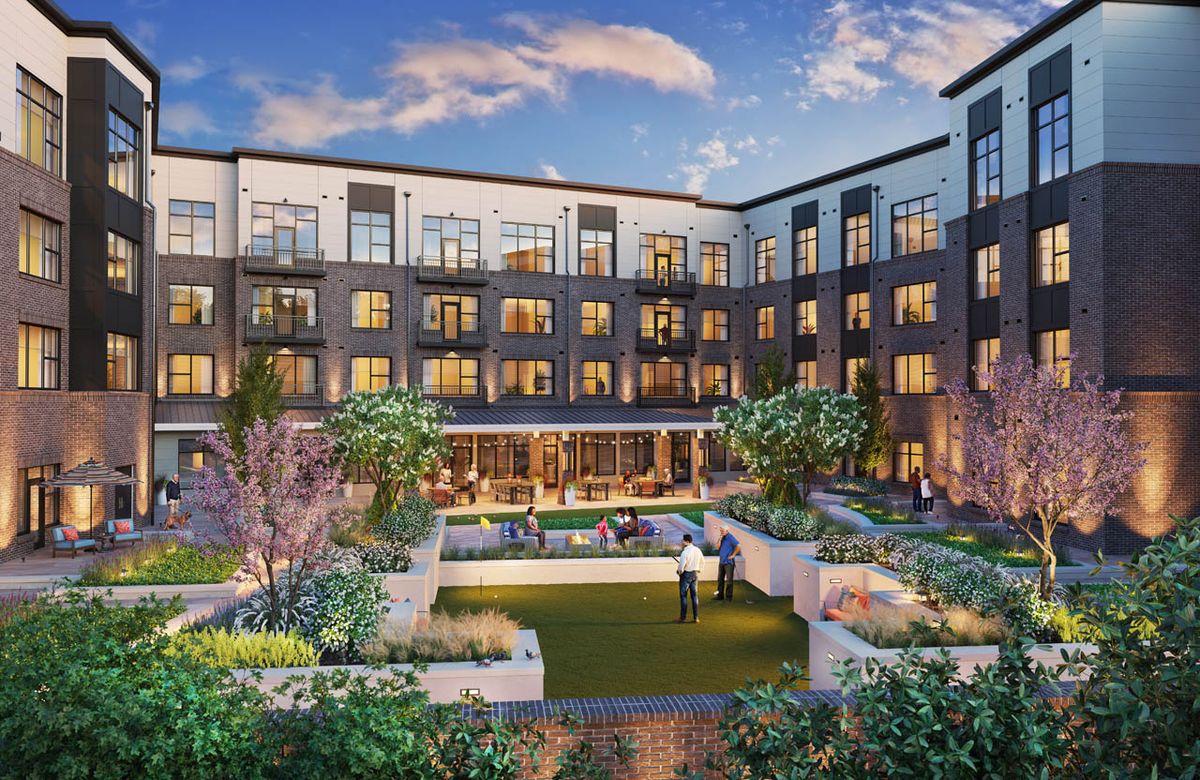 A modern apartment building with a landscaped courtyard in the evening.