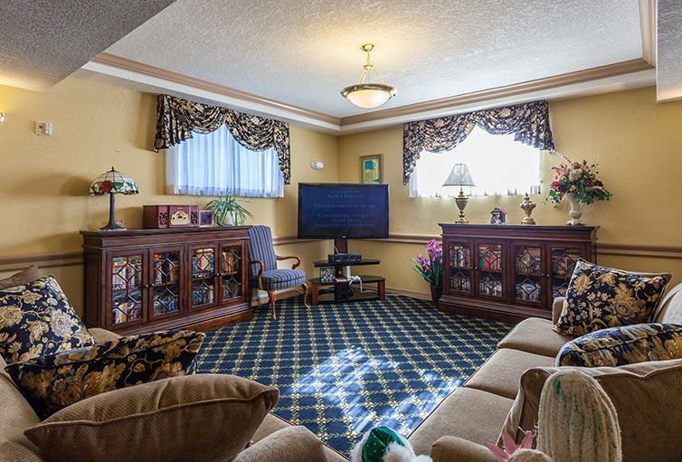 A cozy living room with a television, sofa, and bookshelves adorned with decorative curtains and lamps.