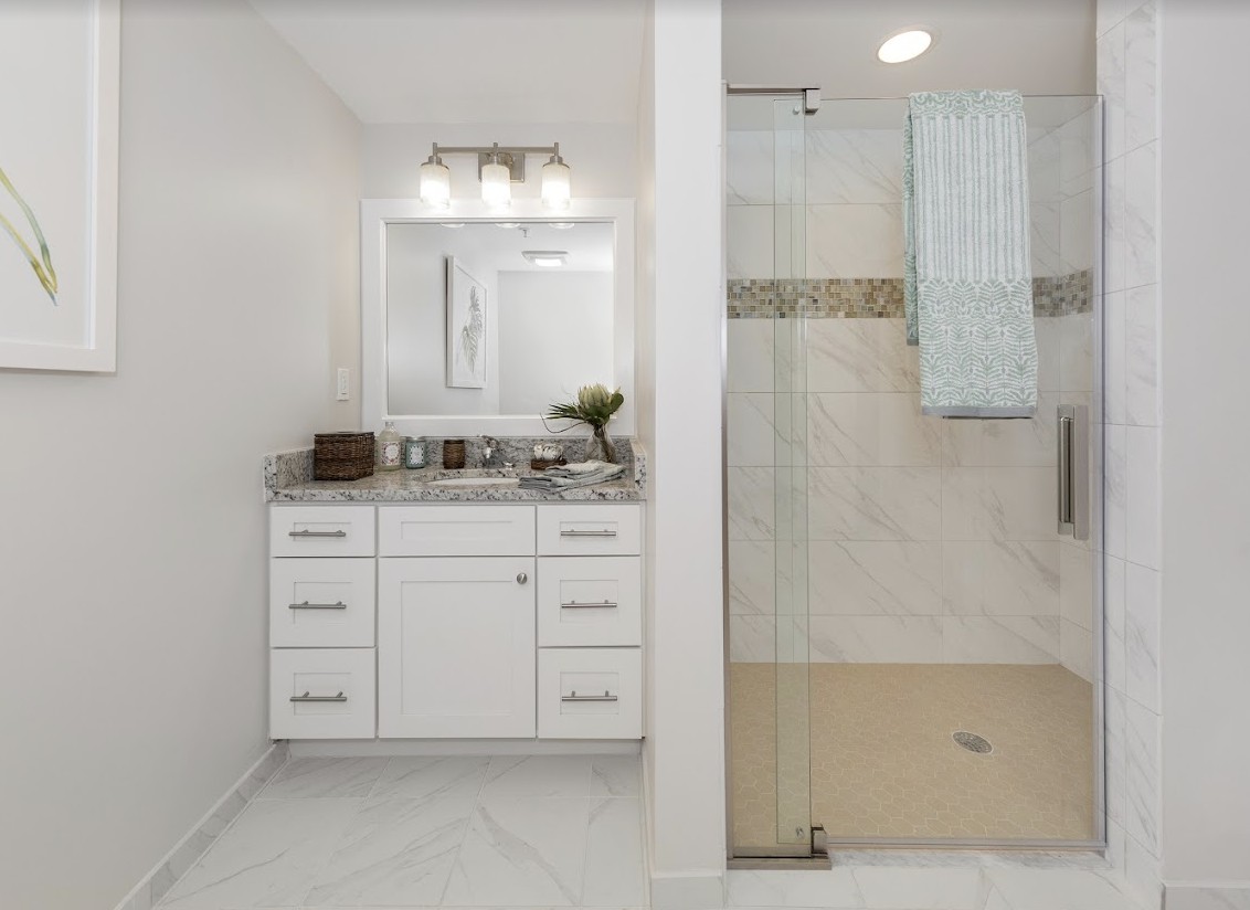 A modern bathroom with a white vanity and a spacious glass-enclosed shower.