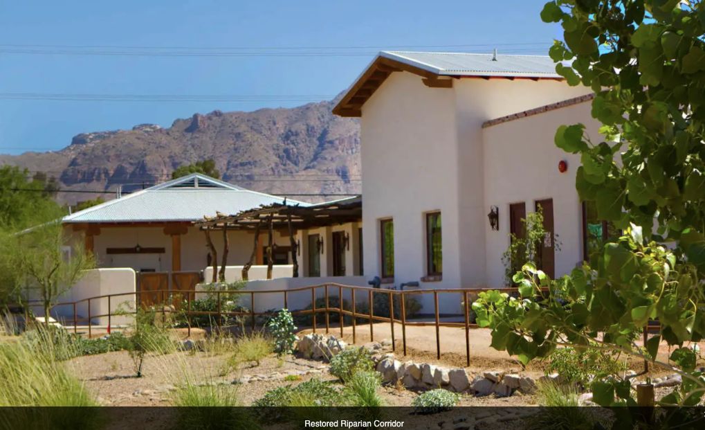 A desert building with mountain views and surrounding plants.