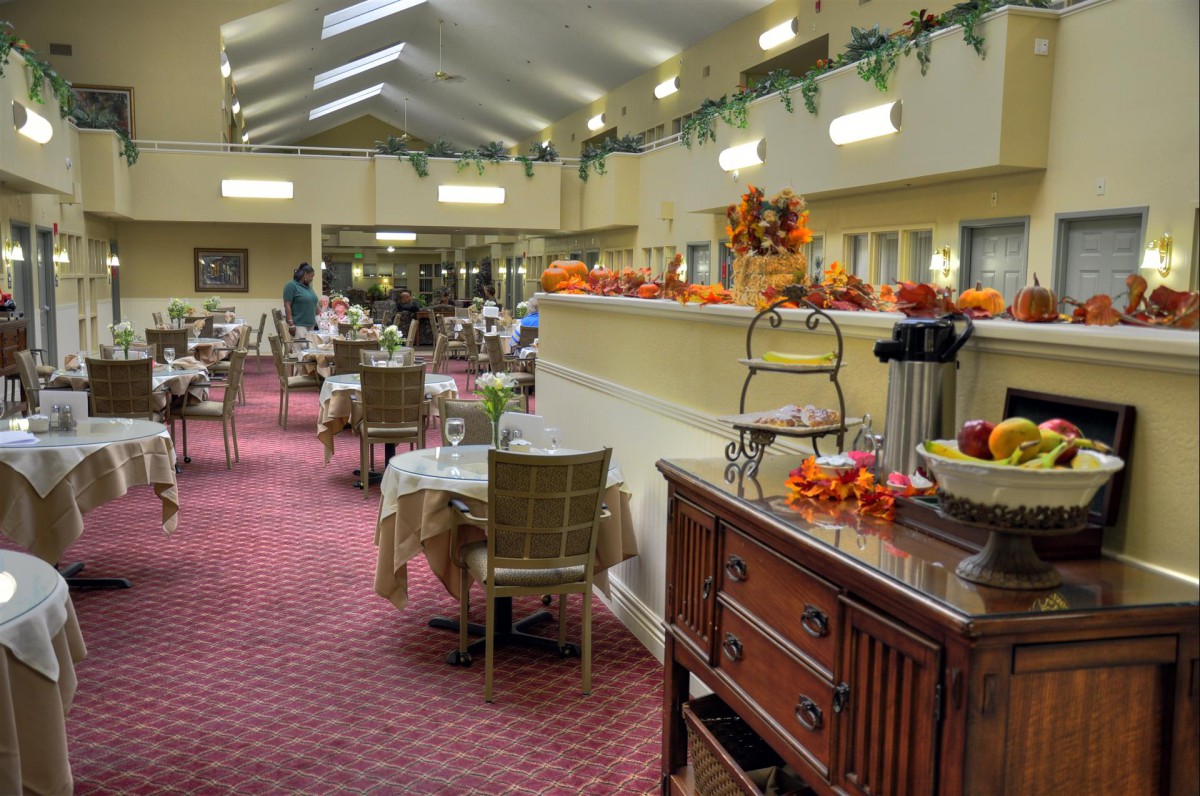 A cozy dining room adorned with autumn decorations, featuring neatly arranged tables and chairs.