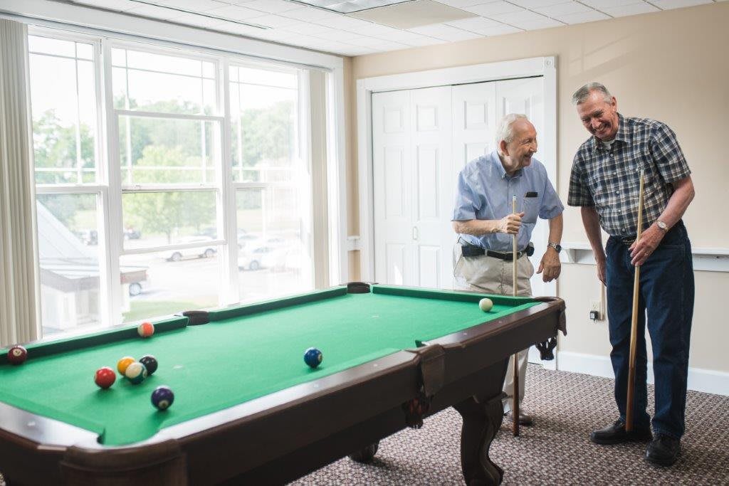Two men enjoying a game of pool indoors.