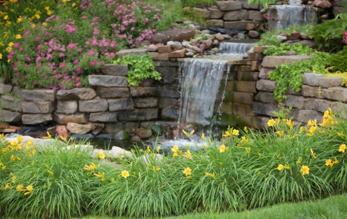 A tranquil garden scene with a cascading waterfall, surrounded by vibrant flowers and lush greenery.