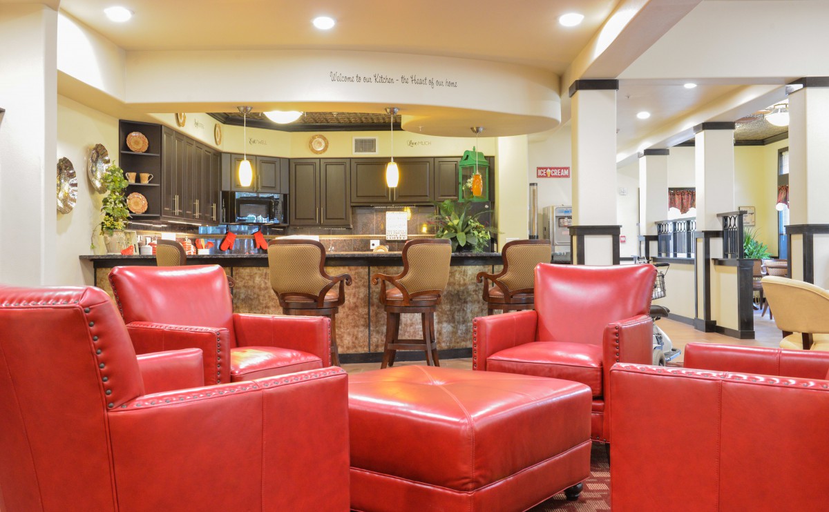 A modern lobby with red chairs and a bar area in the background.