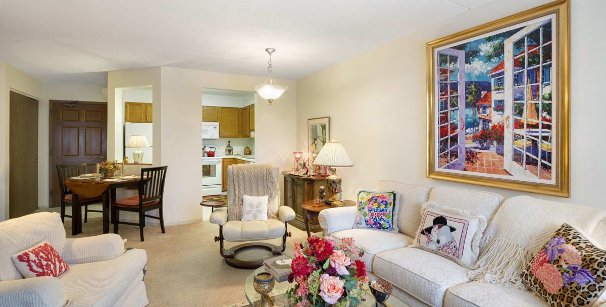 A cozy living room featuring a comfortable sofa and armchair, adorned with decorative pillows and floral accents.