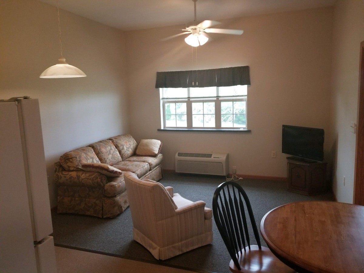 A cozy living room with a sofa, armchair, and dining area.