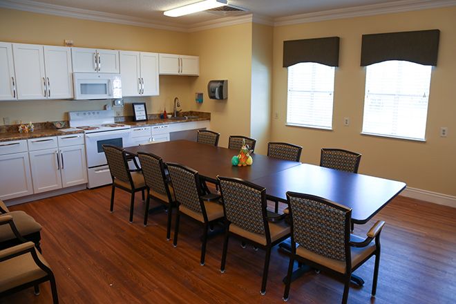 A kitchen and dining area with a long table and multiple chairs, suitable for meetings.