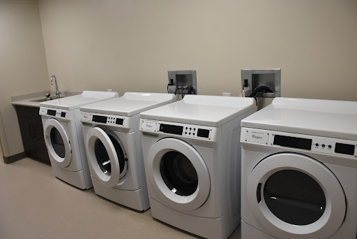 A row of modern washing machines and dryers in a utility space.