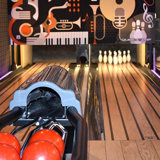 A vibrant bowling alley featuring a modern design with musical elements on the walls.