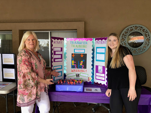 Two women standing next to an educational display board at an event.