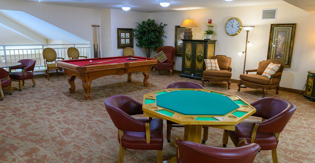 A cozy game room featuring a poker table and a pool table, with comfortable seating for relaxation.