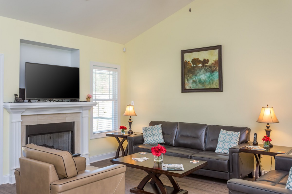 A cozy living room featuring a sofa, coffee table, fireplace, and a mounted TV.