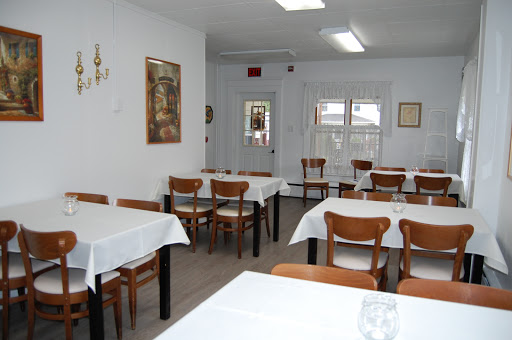 A simple and clean dining area with tables and chairs, waiting for patrons.