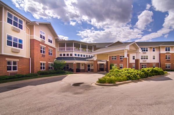 A large residential building with a landscaped entrance under a cloudy sky.