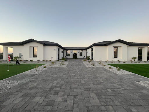 A beautifully designed modern home surrounded by well-maintained landscaping and a spacious paved driveway.