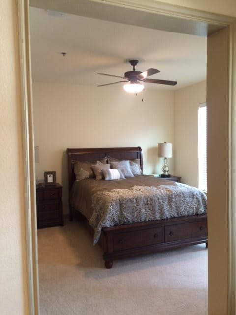 A cozy bedroom with a double bed, decorated with pillows, bedside tables, and a ceiling fan.