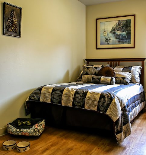 A cozy bedroom featuring a neatly made bed, decorative pillows, and a serene landscape painting.