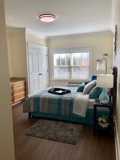 A cozy bedroom with a neatly made bed, decorative pillows, and a soft rug.