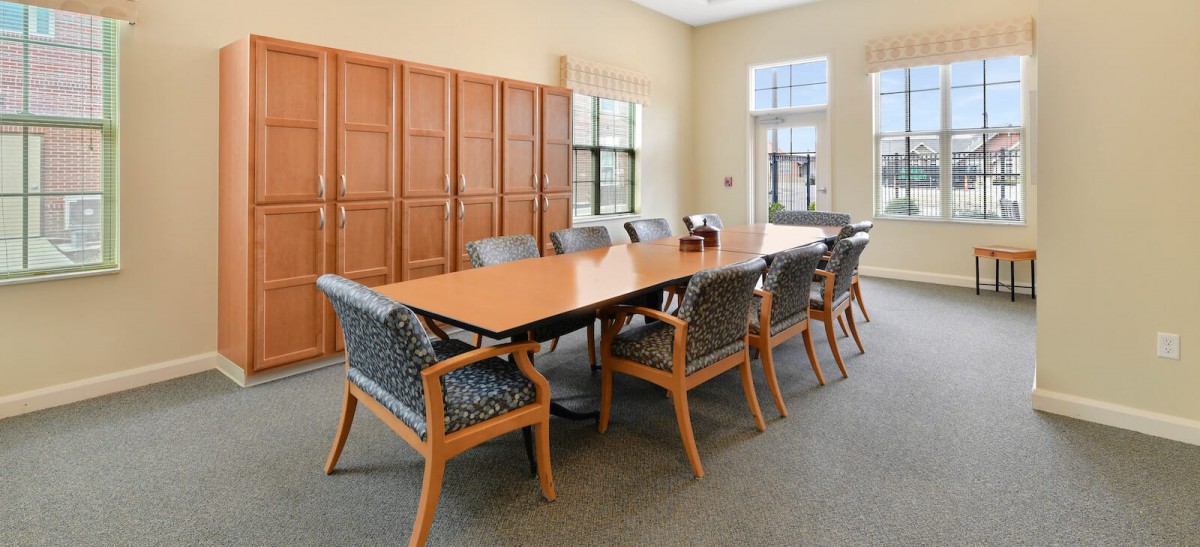 A well-lit conference room featuring a large meeting table surrounded by chairs.
