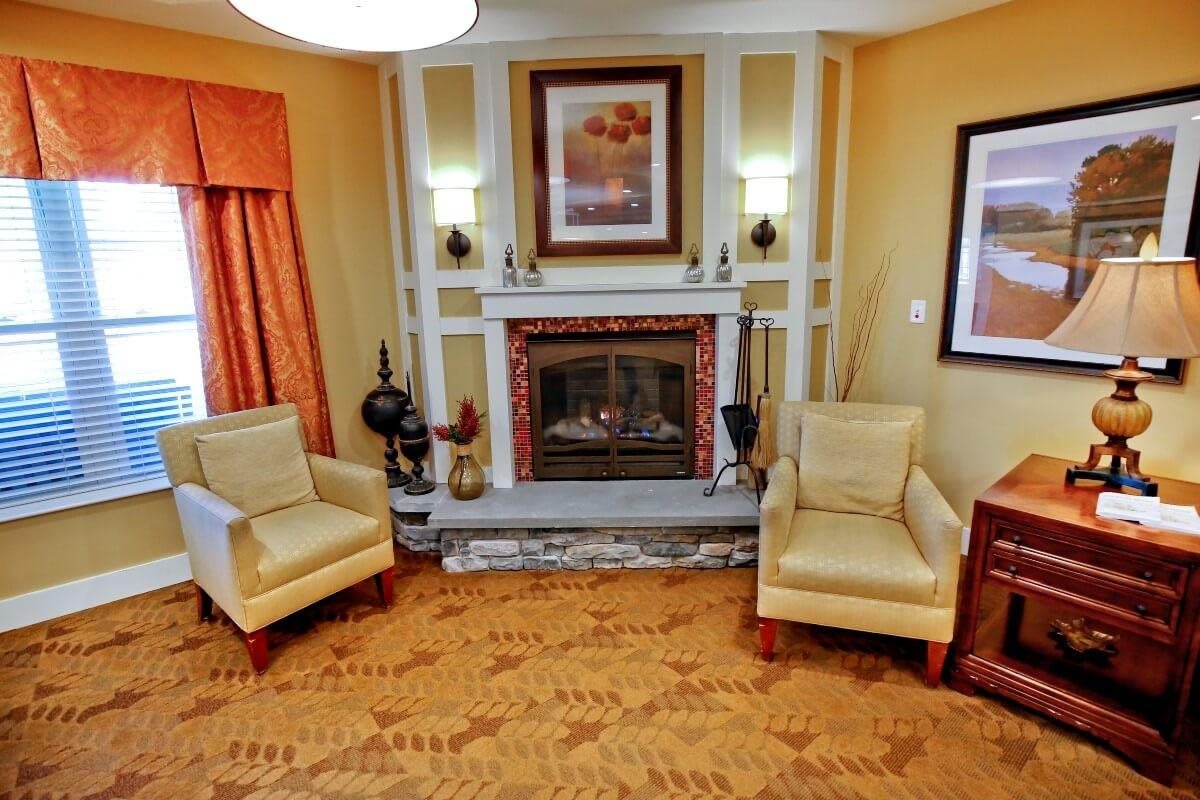 A cozy living room featuring a fireplace, two armchairs, and elegant decor.