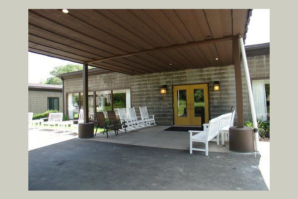 A covered building entrance with several rocking chairs for outdoor seating.